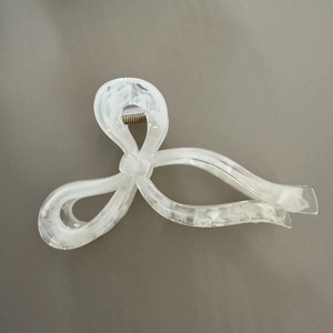 Detailed macro view of white marble texture and gold spring on the acetic acid hair claw
