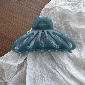 Gros plan détaillé sur une pince à cheveux bleu foncé translucide en forme d'éventail