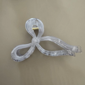 Detail of large bow hair claw clip with grey marble texture and gold metal spring