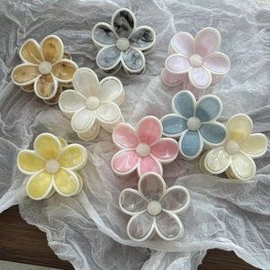 Lot de pinces à cheveux en acétate marbré en forme de fleur sur tissu blanc doux