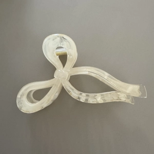 Detail view of large cream marble acetate hair claw clip with golden metal spring