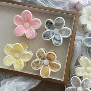 Détail de pinces à cheveux fleur en acétate marbré avec ornements centraux perle