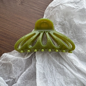 Détail d'une grande pince à cheveux évidée en forme d'éventail vert olive brillant