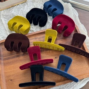 Close-up of velvet-flocked M-shape shark clips in various autumn colors on a wooden tray