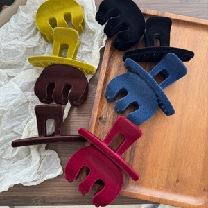 Set of five velvet flocked hair claw clips in autumn colors on a wooden tray