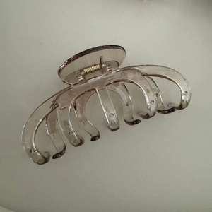 Gros plan d'une grande pince à cheveux citrouille avec ressort en métal doré et dents