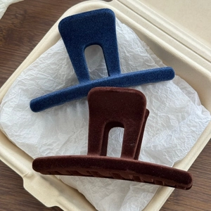 Close-up of navy and brown flocked M-shaped claw clips with soft velvet texture