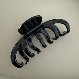 Détail macro d'une grande pince à cheveux noire brillante au fini lisse poli