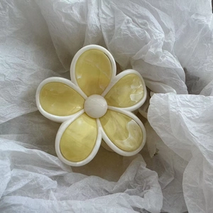 Gros plan sur la pince à cheveux fleur jaune marbré avec bordures blanc ivoire