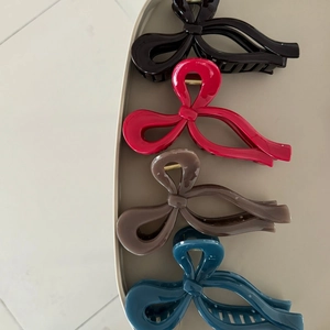 Dettaglio di un set di quattro fermagli per capelli in resina lucida nera, rossa e blu