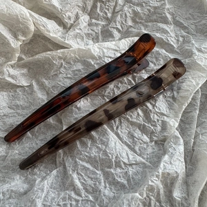 Close-up of tortoise shell leopard print hair clips on white textured background