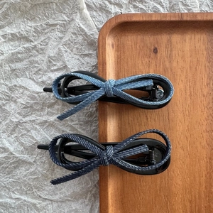 Detail view of denim texture bow hair clips with metal springs on a wooden tray