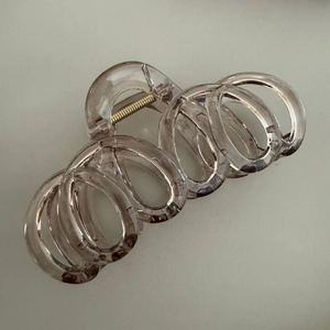 Gros plan sur une grande pince à cheveux beige transparent avec ressort doré