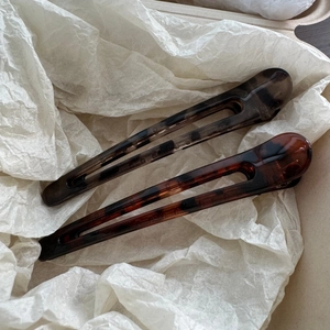 Detailed macro view of two leopard print resin hair clips on white crinkled paper