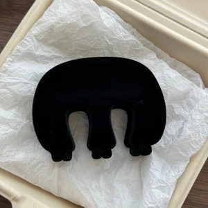 Detail view of a black flocked M-shaped shark hair clip with a velvet texture finish