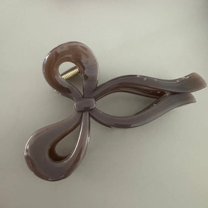 Dettaglio macro di un grande fermaglio per capelli a fiocco marrone in acetato