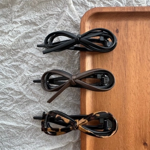Detailed view of three leopard print and leather bow hair clips on a wooden tray
