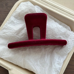 Macro shot of deep red flocked velvet M-shaped hair claw clip on soft paper texture