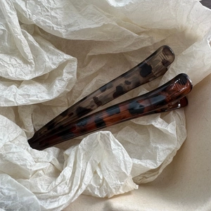 Close-up of two leopard print hair clips with tortoiseshell pattern on white tissue