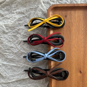 Set of four velvet bow hair clips in multiple colors displayed on a wooden tray