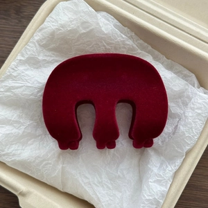 Macro detail of wine red velvet M-shaped hair claw clip with a plush texture in a gift box