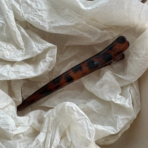 Macro shot of long tortoiseshell patterned hair clip on textured white paper background