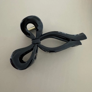 Dettaglio di una pinza per capelli nera lucida a forma di fiocco con molla in metallo