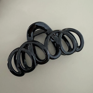Détail de la structure en spirale noire brillante et du ressort métallique de la pince à cheveux