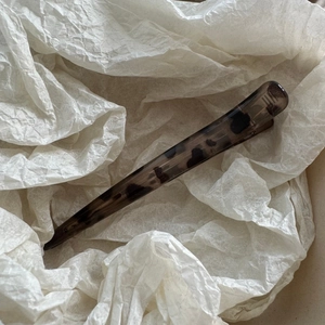 Detail view of large leopard print hair clip on textured white paper background