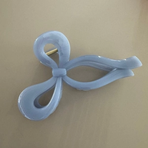 Dettaglio del fermaglio a fiocco azzurro con trama marmorea e molla in metallo dorato