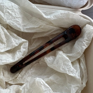 Detailed view of the tortoiseshell U-shaped hair pin on white textured paper