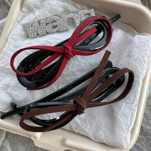 Close-up of leopard print and velvet bow hair clips in burgundy and deep brown