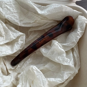 Detail view of the brown leopard pattern hair clip resting on white tissue paper