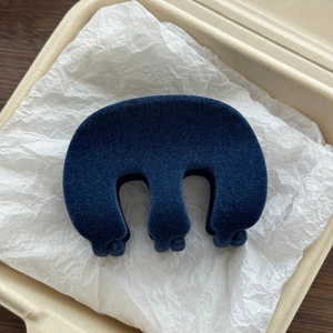 Detailed view of a dark blue flocked shark hair claw clip in a minimalist box setting