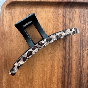 Vue détaillée de la pince à cheveux vintage motif léopard sur un plateau en bois texturé