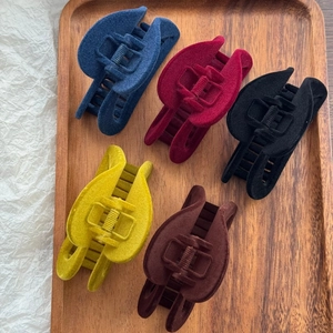Détail de cinq pinces à cheveux en velours bleu marine, bordeaux, noir et jaune