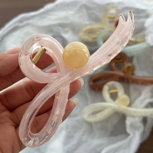 Dettaglio della molletta per capelli in resina rosa chiaro con molla dorata e perla