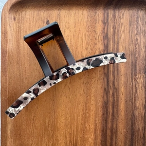 Détail macro de la grande pince à cheveux léopard avec motif vintage en résine sur bois