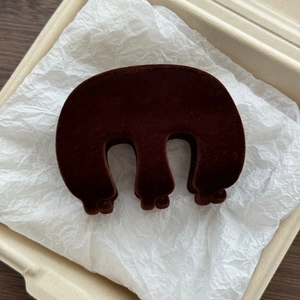 Detail of a dark brown flocked shark hair clip with a unique M-shaped luxury design