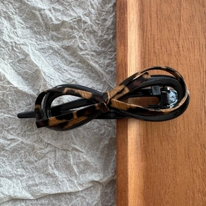 Detailed top view of leopard print bow hair clip with metal spring and resin base