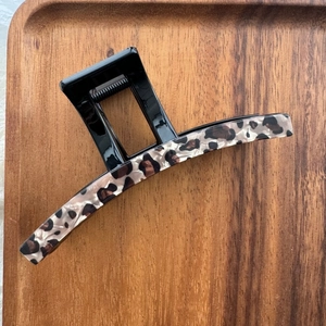 Gros plan d'une pince à cheveux motif léopard avec ressort solide sur support bois