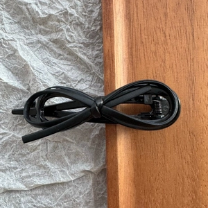 Detail view of the black faux leather bow hair clip with a vintage metal duckbill clamp