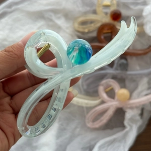 Dettaglio ravvicinato di grandi mollette per capelli in resina marmorizzata in vari colori