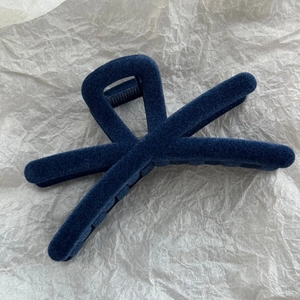 Vue détaillée de la pince à cheveux en velours bleu foncé avec un design croisé élégant