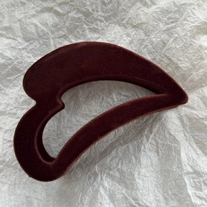 Détail de la pince à cheveux floquée marron avec texture velours sur fond de papier blanc