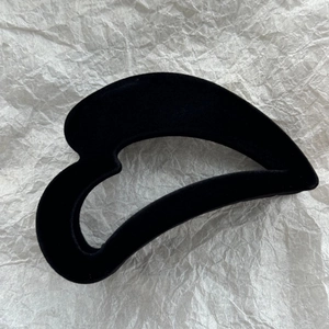 Gros plan d'une pince à cheveux en velours noir en forme de cœur au fini vintage