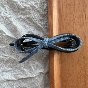 Detailed macro view of the denim fabric bow and black round hair clip on a textured background