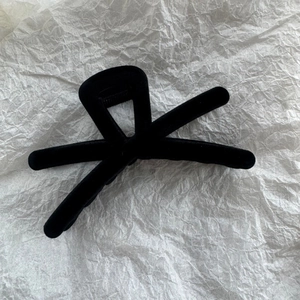 Vue détaillée de dessus d'une grande pince à cheveux floquée noire sur papier texturé