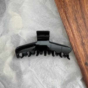 Détail d'une pince à cheveux noire brillante en PC avec design ondulé pour cheveux épais
