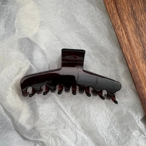 Gros plan détaillé de la pince à cheveux en résine marron foncé avec de grandes dents